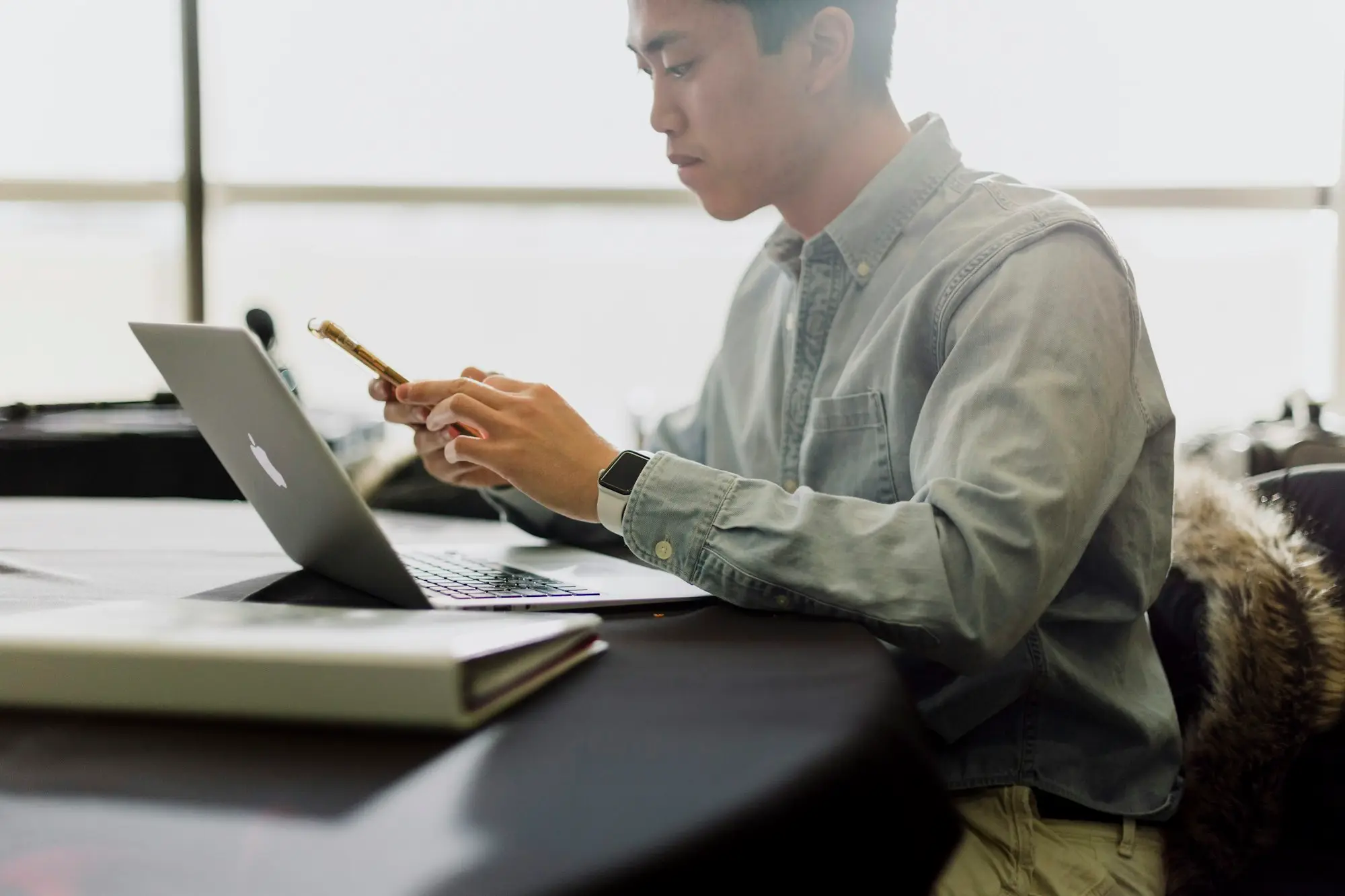 Business owner checking invoices on a phone beside a laptop