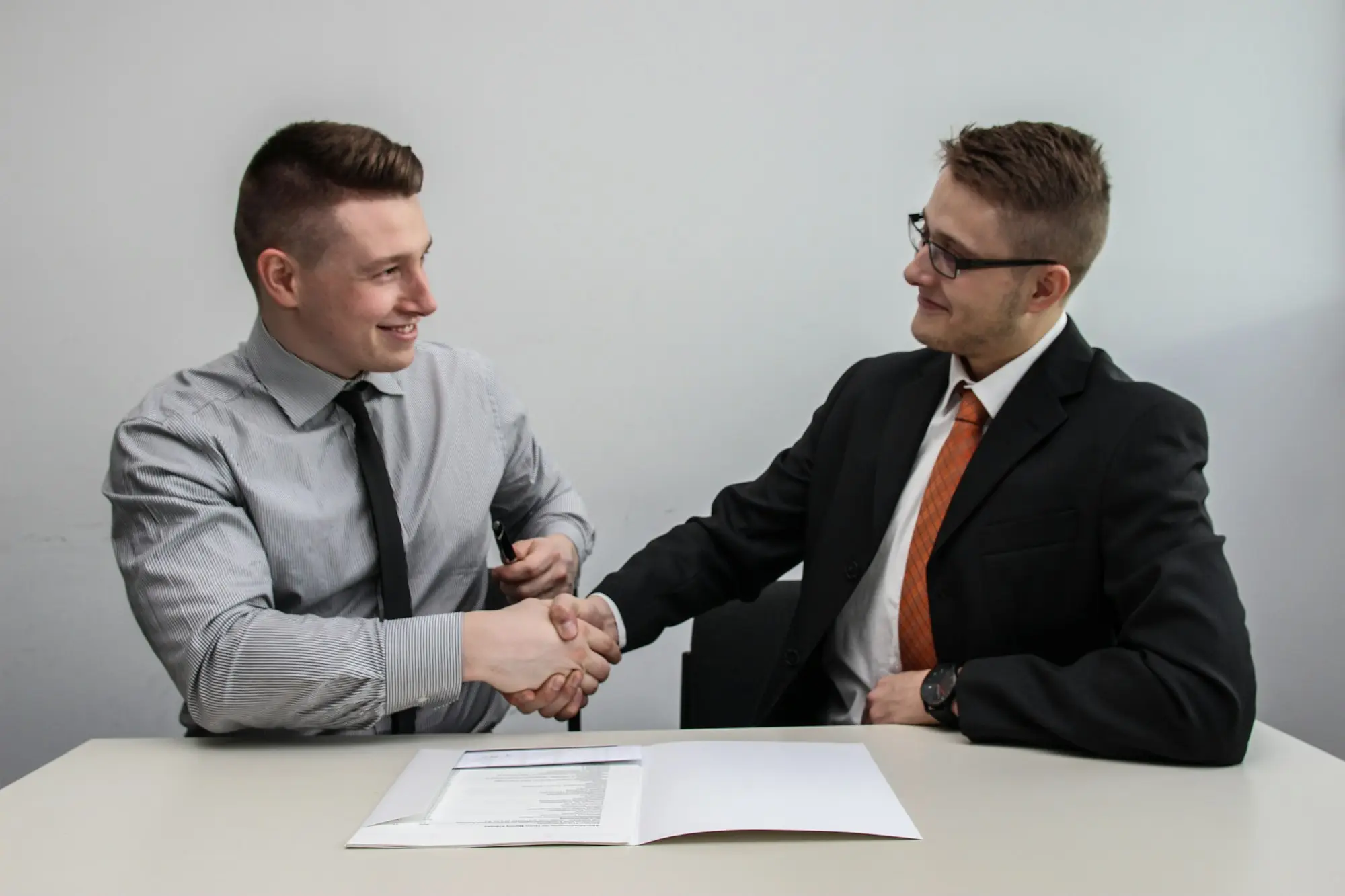 Buyer and seller shaking hands over a business sale agreement