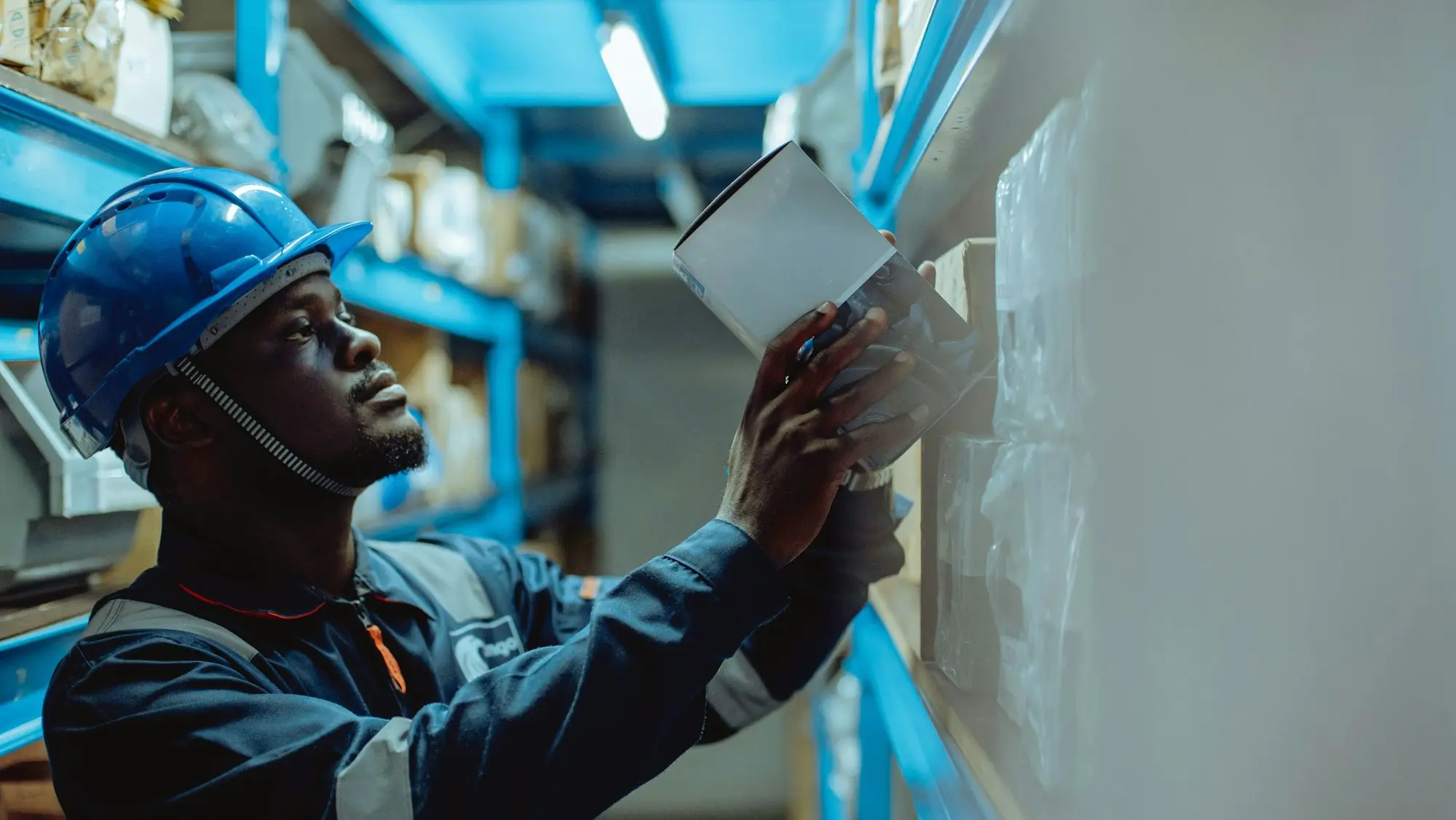 Warehouse worker in a hard hat checking stock on the racking